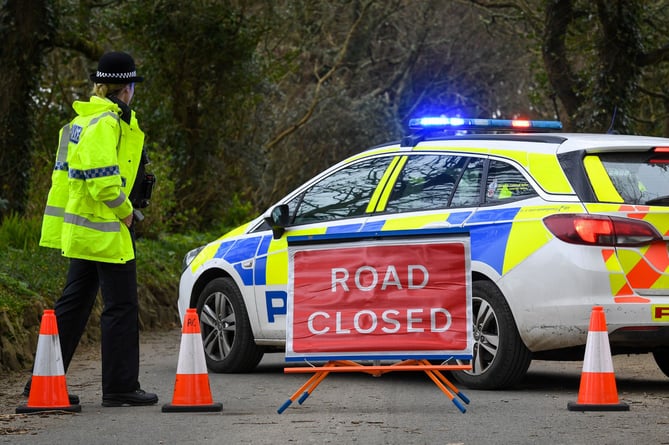 Police officer with road closed sign and police vehicle